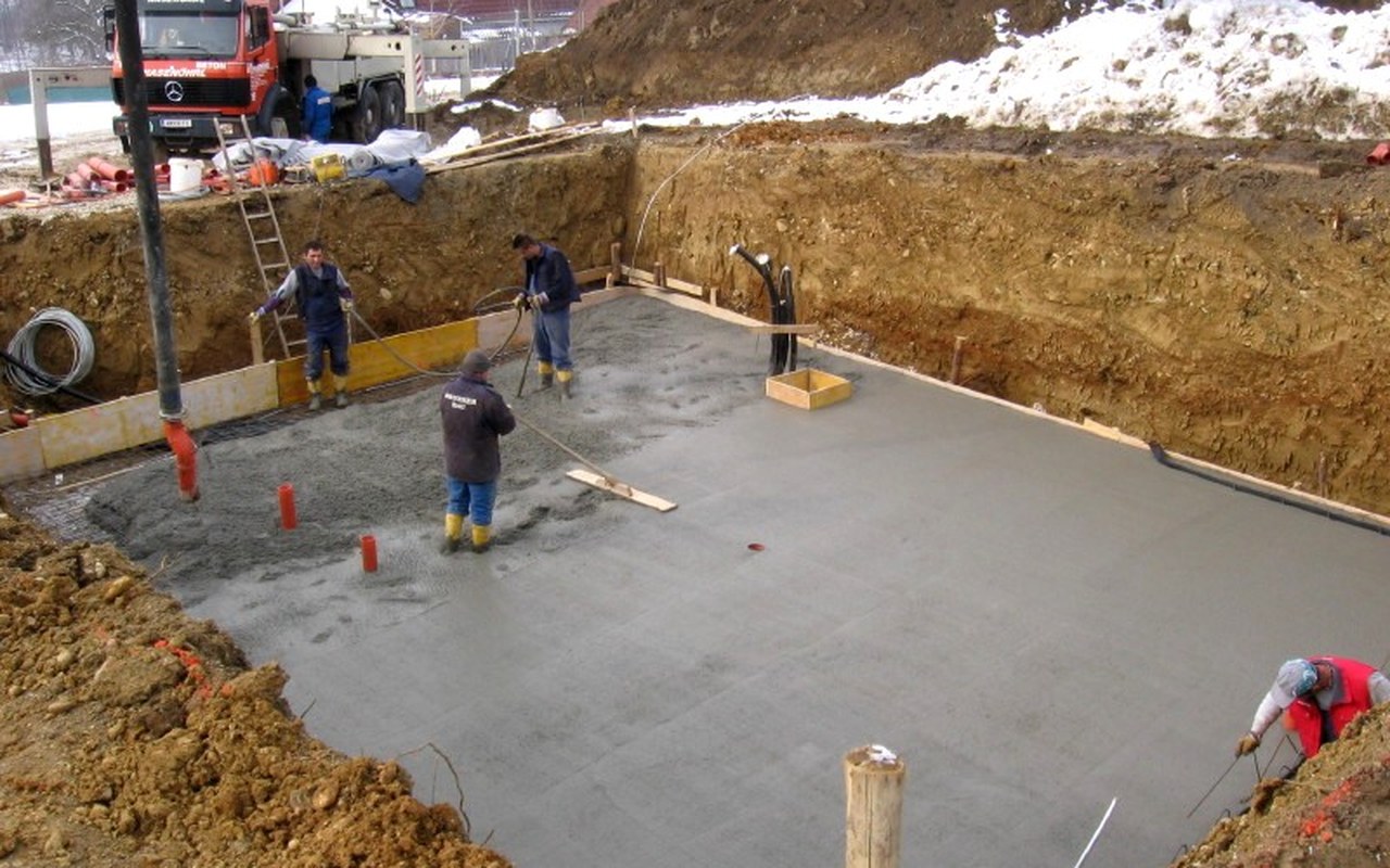 Workers pouring wet concrete into a form