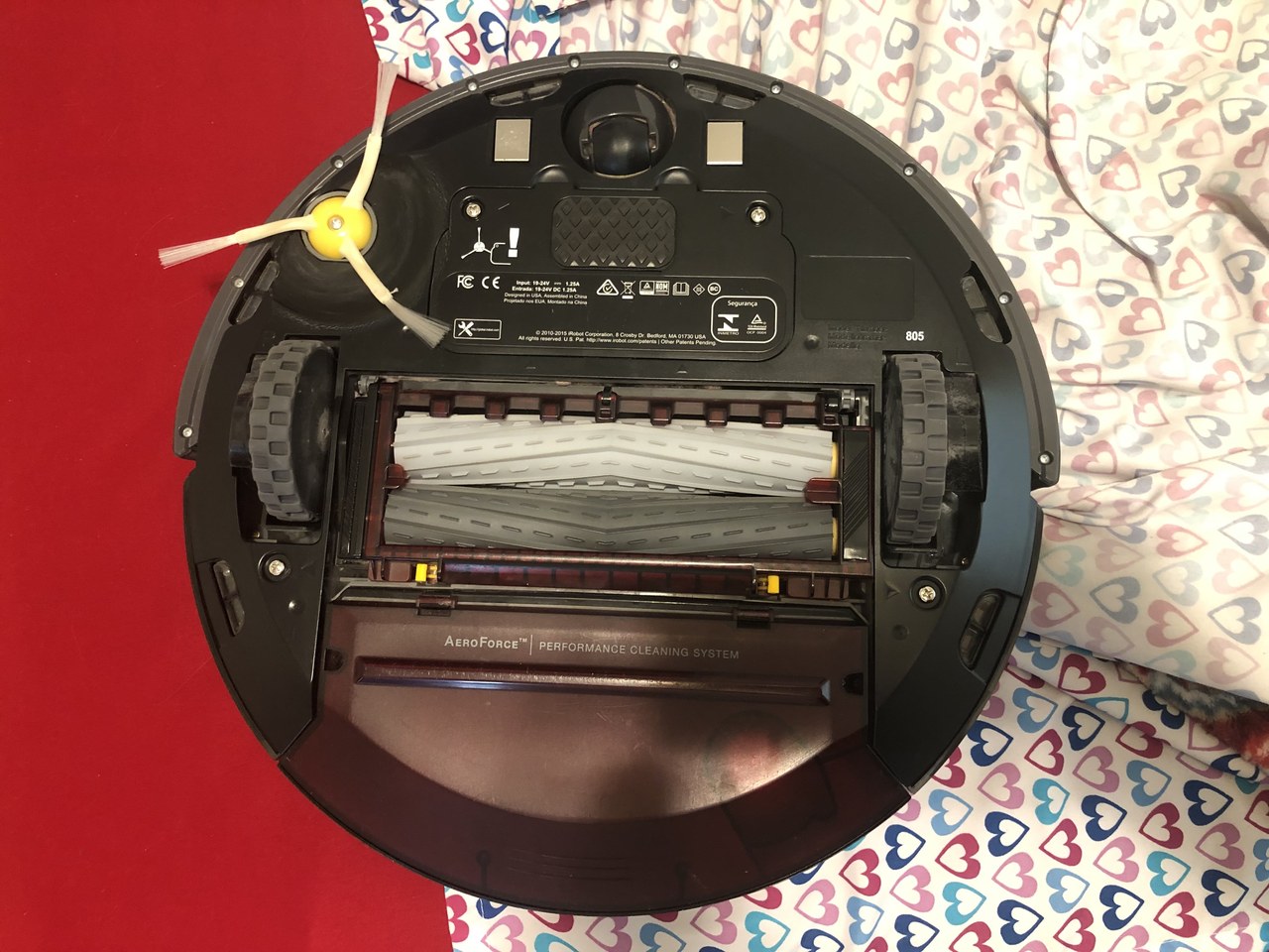Underside of a robot vacuum showing main brush, side brush, and wheels