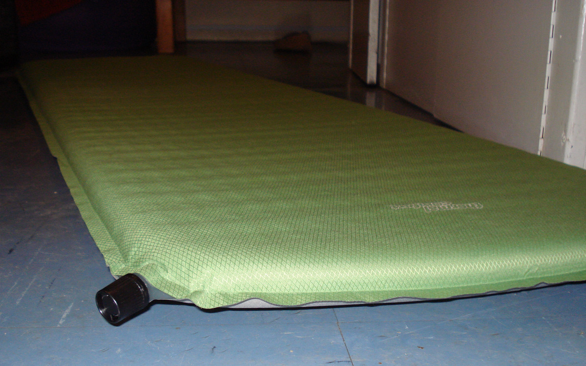 Self-inflating camping sleeping mat partially unrolled outdoors
