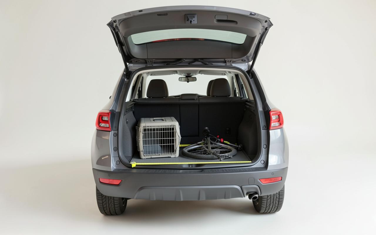 Open rear cargo area of a compact electric SUV with a tape measure across the floor, a dog crate and a folded bike loaded